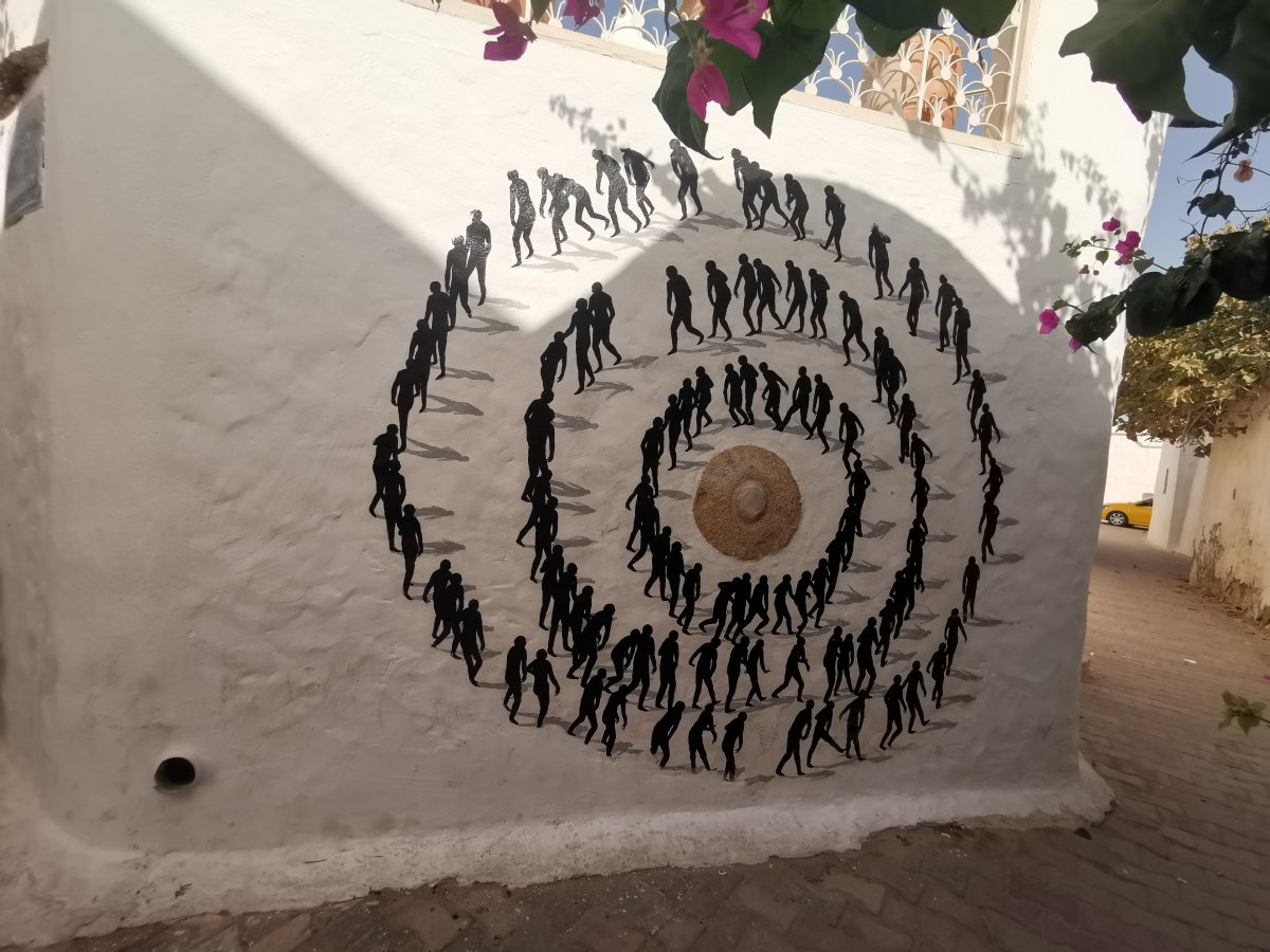 Ein gemaltes Bild auf einer weissen Wand: Drei Kreise mit Menschen, die im Gegenuhrzeigersinn gehen.